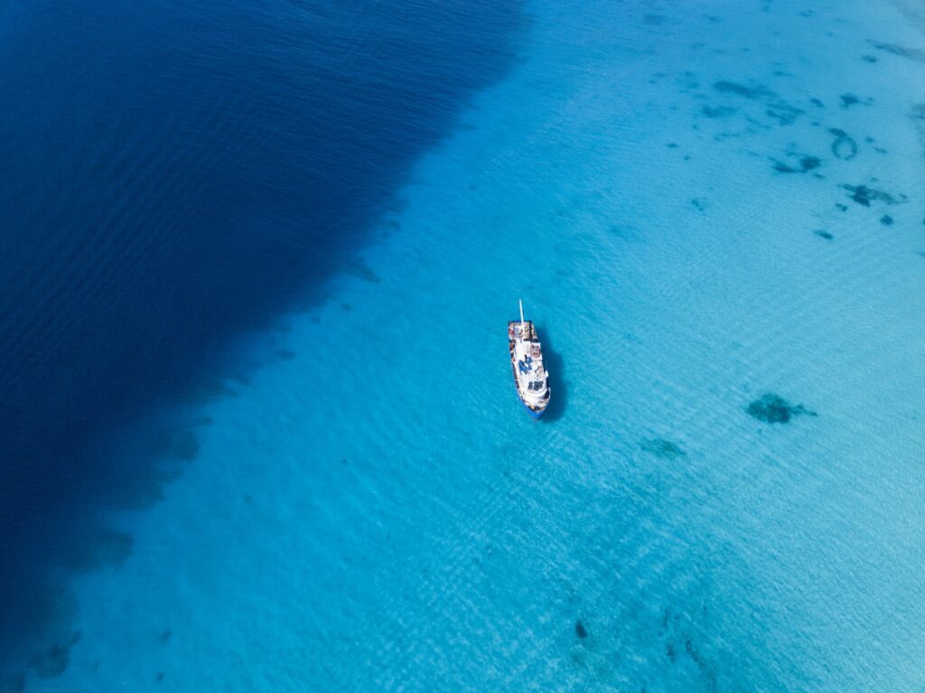 Aerial view of ship floating over crystal clear waters of Grand