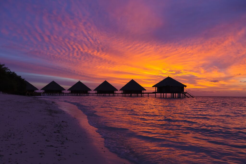 Sunset in the Maldives with a view of the lagoon and bungalows